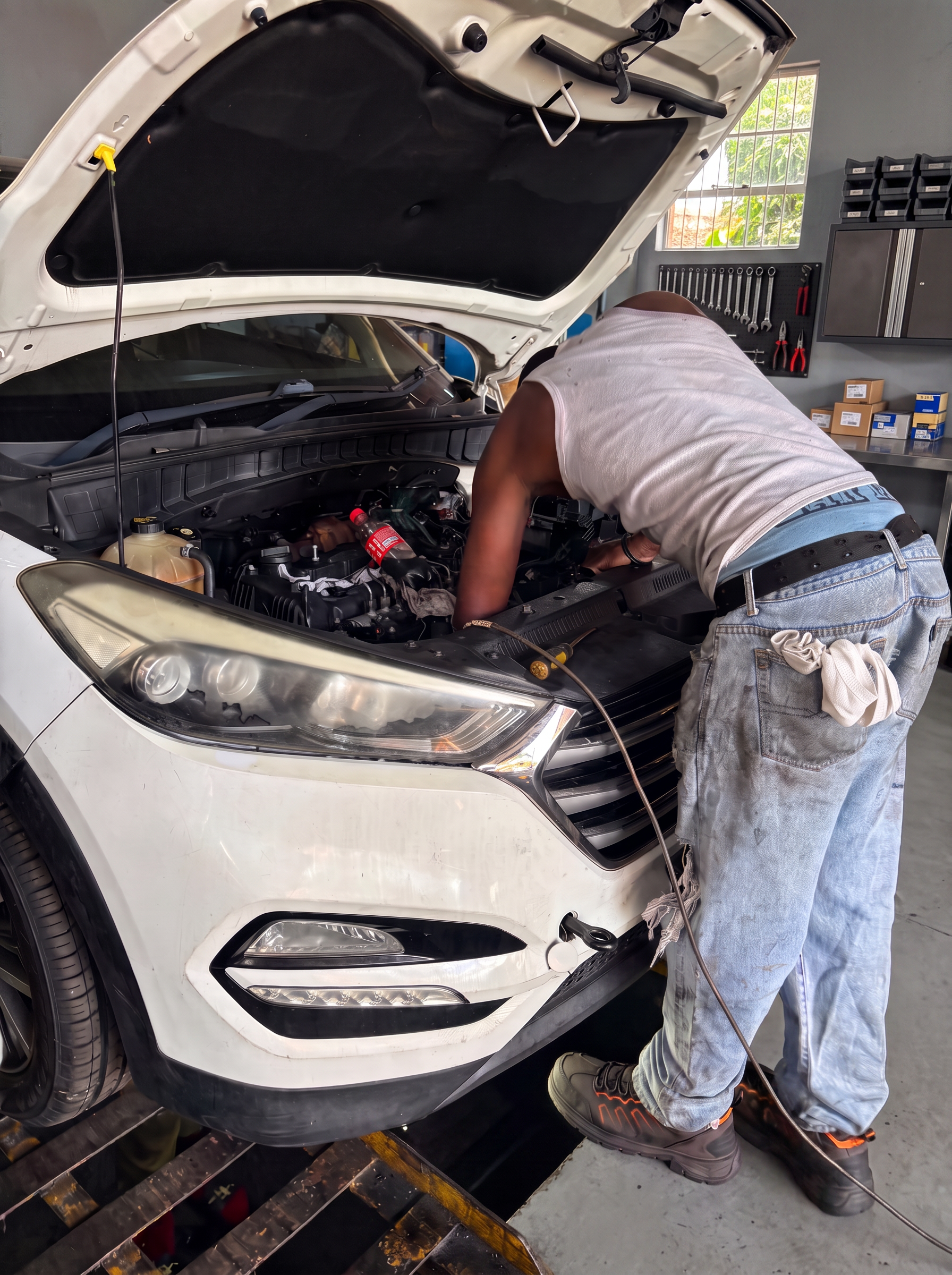 OJMG auto technician diagnosing an engine under the hood in the Arouca workshop